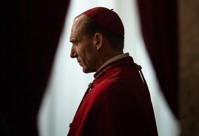Ralph Fiennes in profile looking thoughtful as Cardinal Lawrence in a scene from Conclave