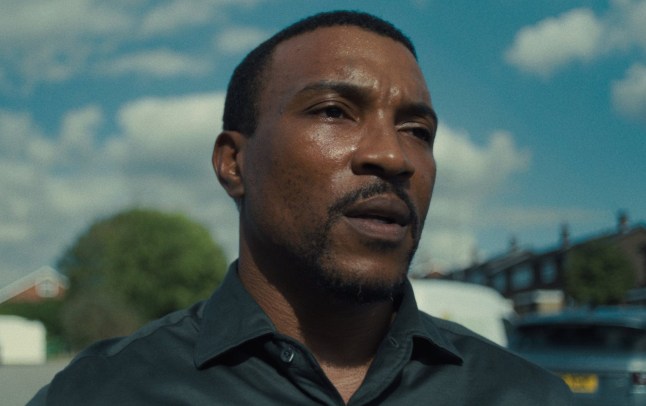 Ashley Walters as Detective Inspector Bascombe walking down a residential street in Netflix show Adolescence