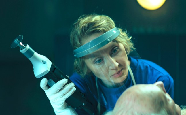 A still from the Netflix show Woman of the Dead of a woman in medial protective suit with a threatening look on her face