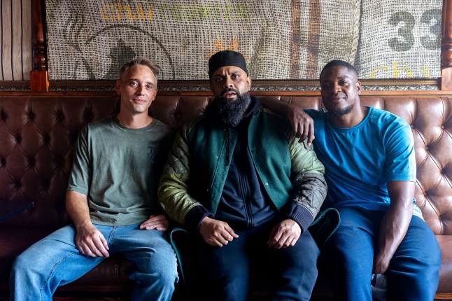 Perry Fitzpatrick as Officer Harper, Guz Khan as Mobeen and Tolu Ogunmefun as Nate sat on the sofa in casual clothing on Man Like Mobeen